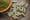 Kratom green capsules and powder on brown plate. 