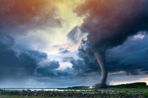 Tornado forming destruction over a populated landscape with a home or house on the way.